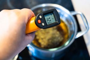 someone holding a thermometer over a pot